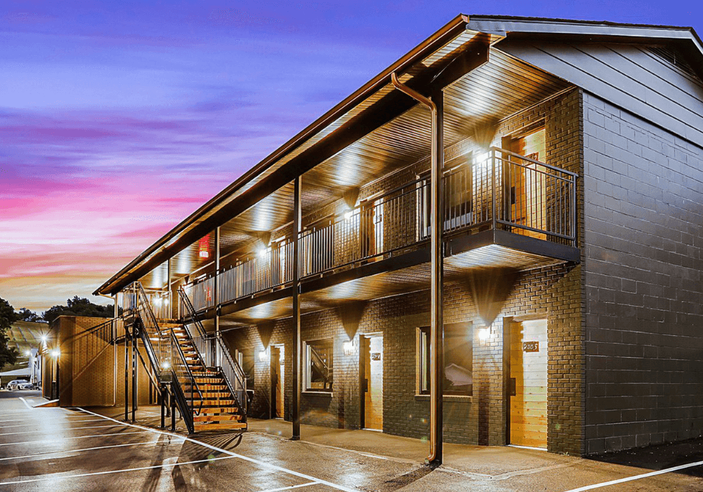 A modern, two-story motel exterior illuminated at dusk.