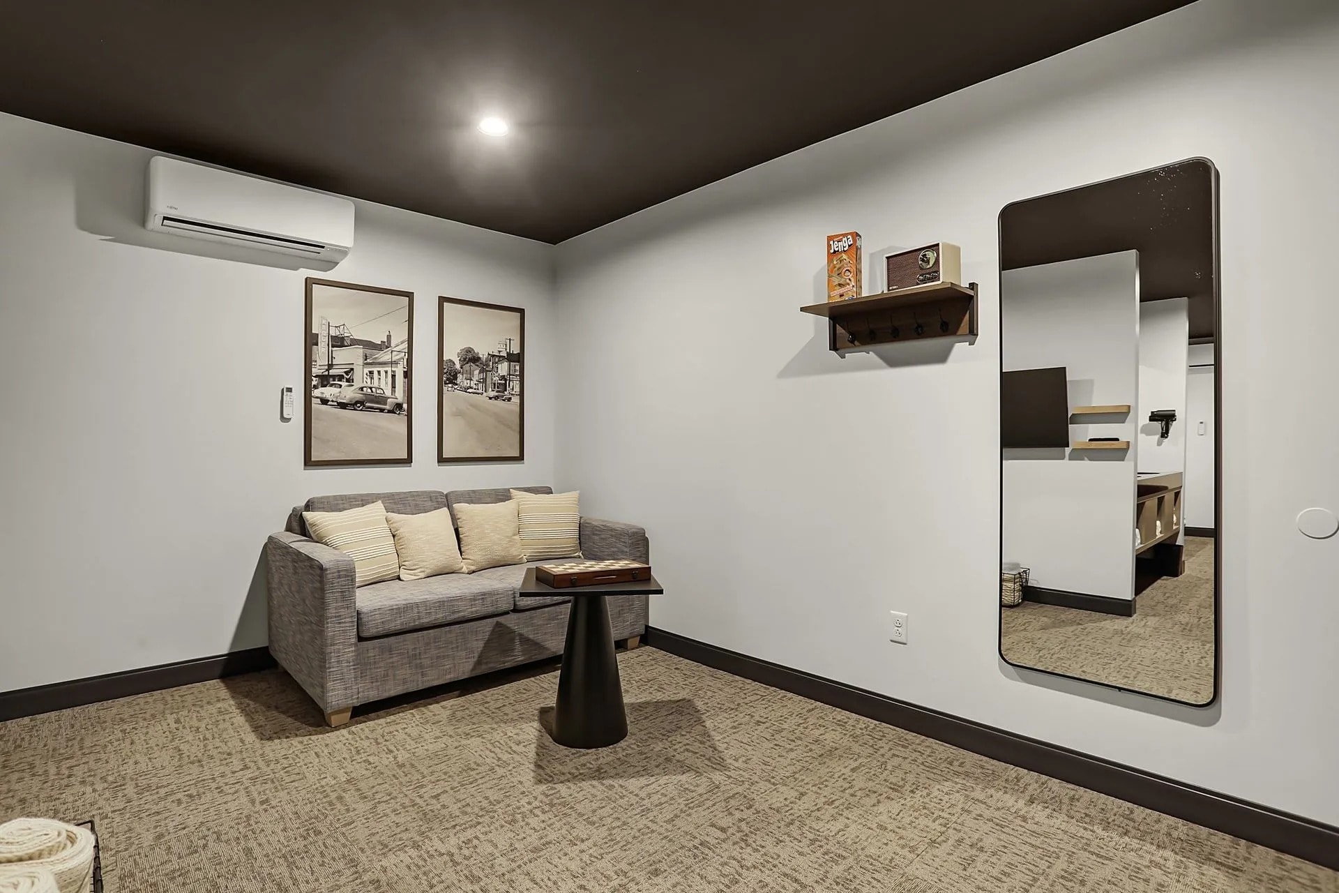 A modern room featuring a gray sofa, two framed pictures, a sleek mirror, and a small table.