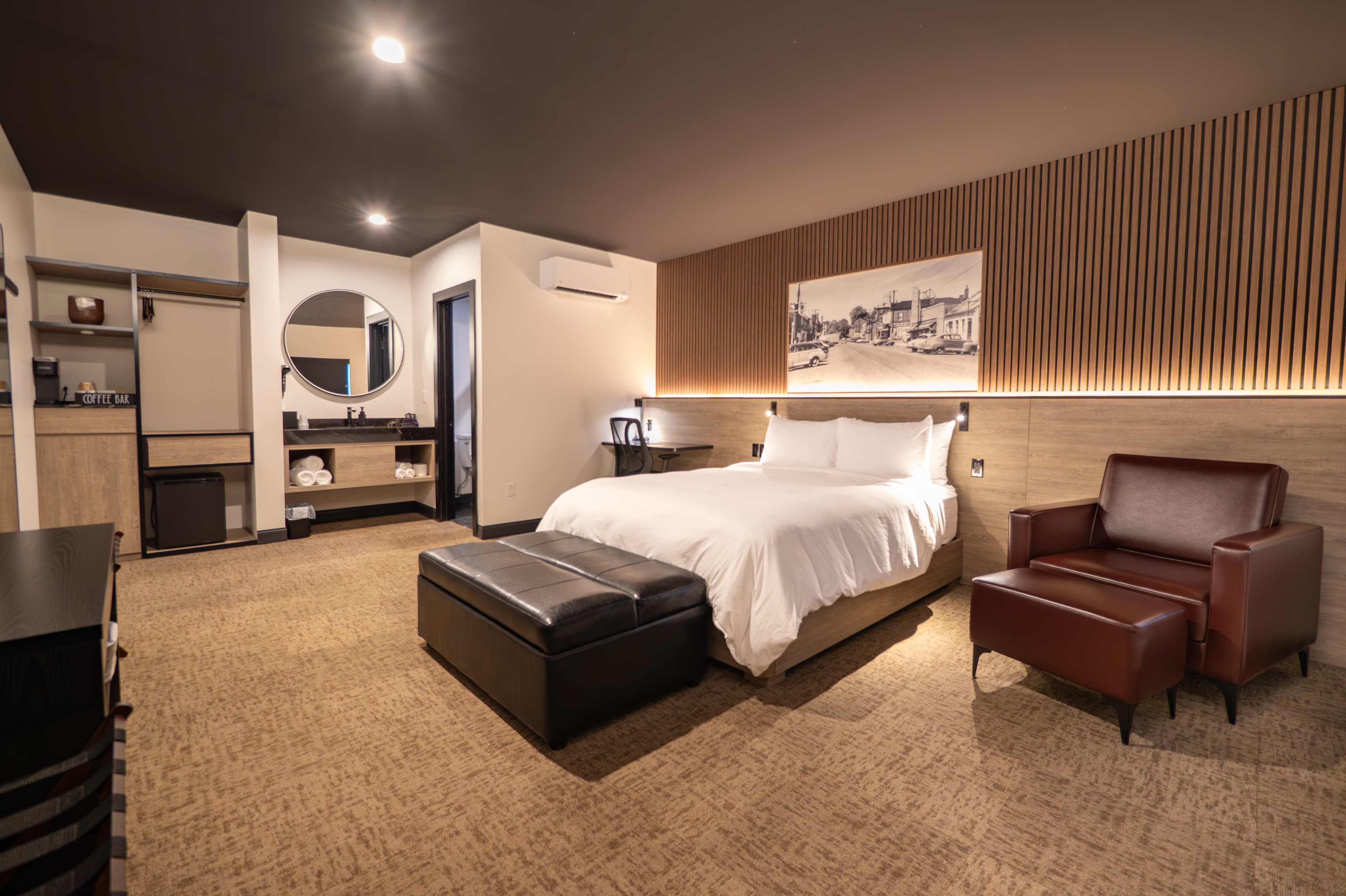 Modern hotel room featuring a large bed, seating area, and warm wood accents.