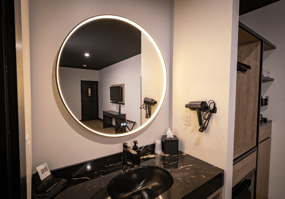 Modern bathroom featuring a circular mirror, black basin, and stylish decor.
