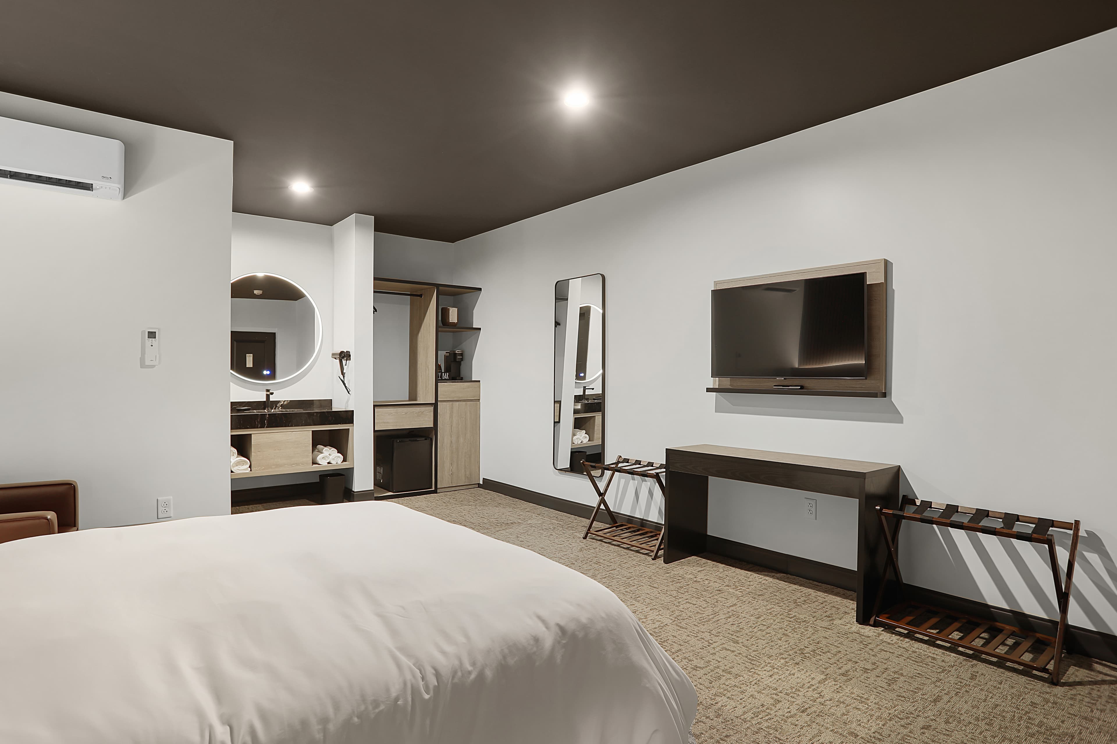 Modern hotel room featuring a bed, TV, mirror, and stylish furnishings.