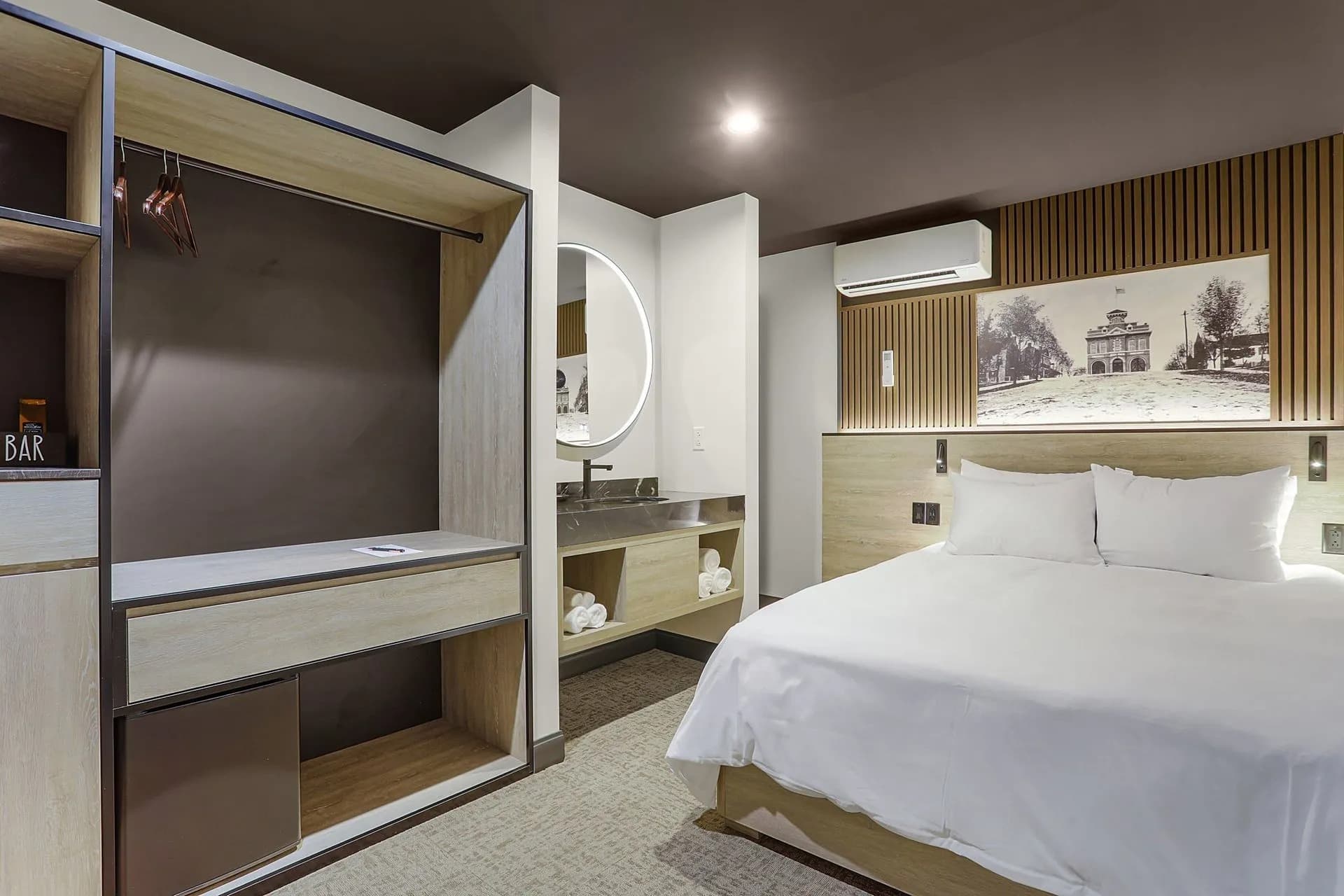 Modern hotel room featuring a queen bed, minimalist decor, and a stylish workspace.