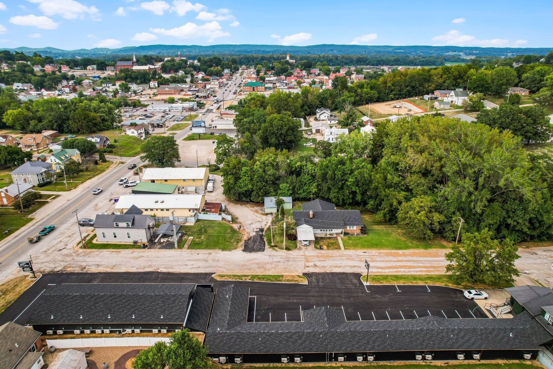 Aerial view of a small town with residential areas, commercial buildings, and green spaces.