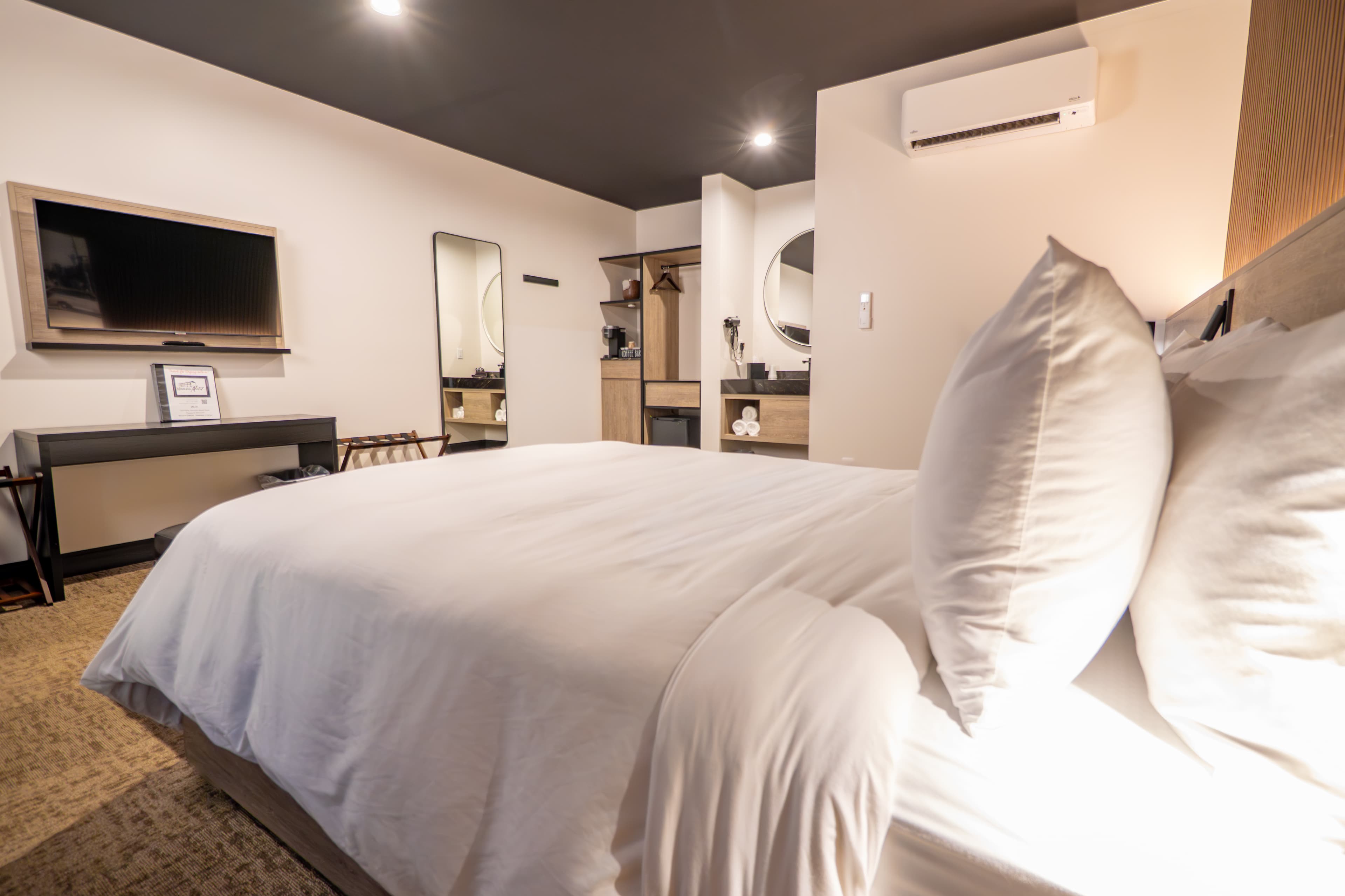 A modern bedroom featuring a neatly made bed, television, and stylish decor.
