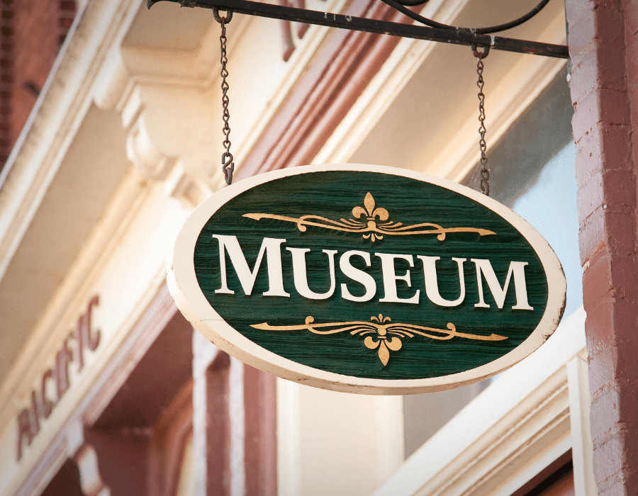 A green and white sign reading "MUSEUM" hanging outside a building.