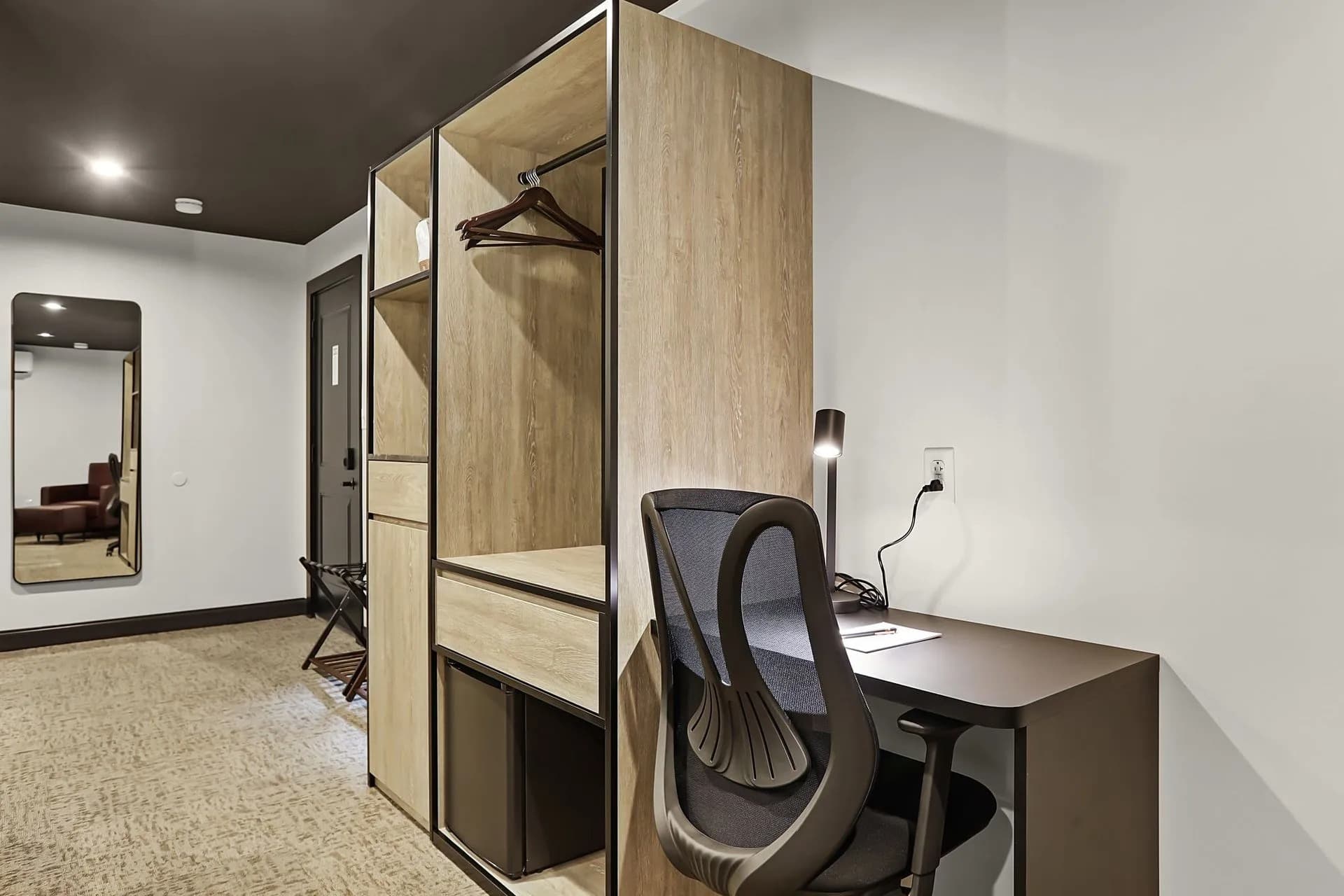 A modern room featuring a wooden wardrobe and a desk with a chair.