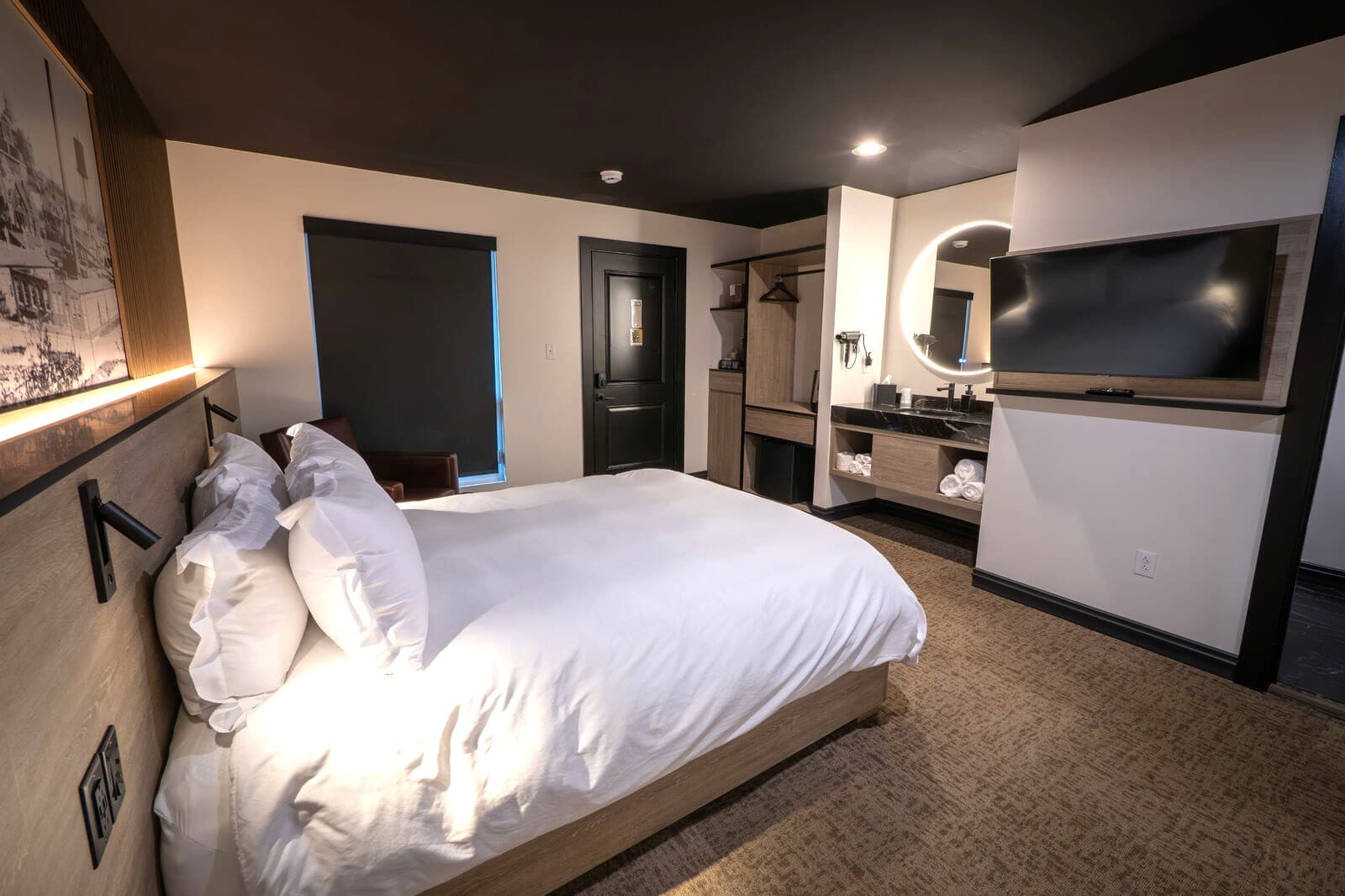 A modern hotel room with a bed, TV, and bathroom features.