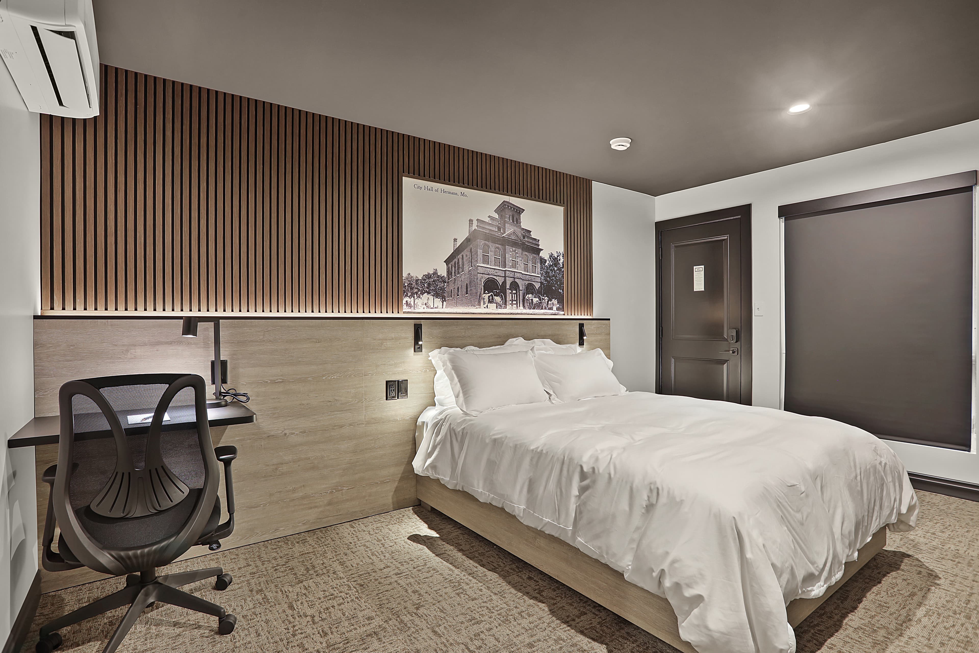 A modern bedroom featuring a double bed, desk, and decorative wall art.