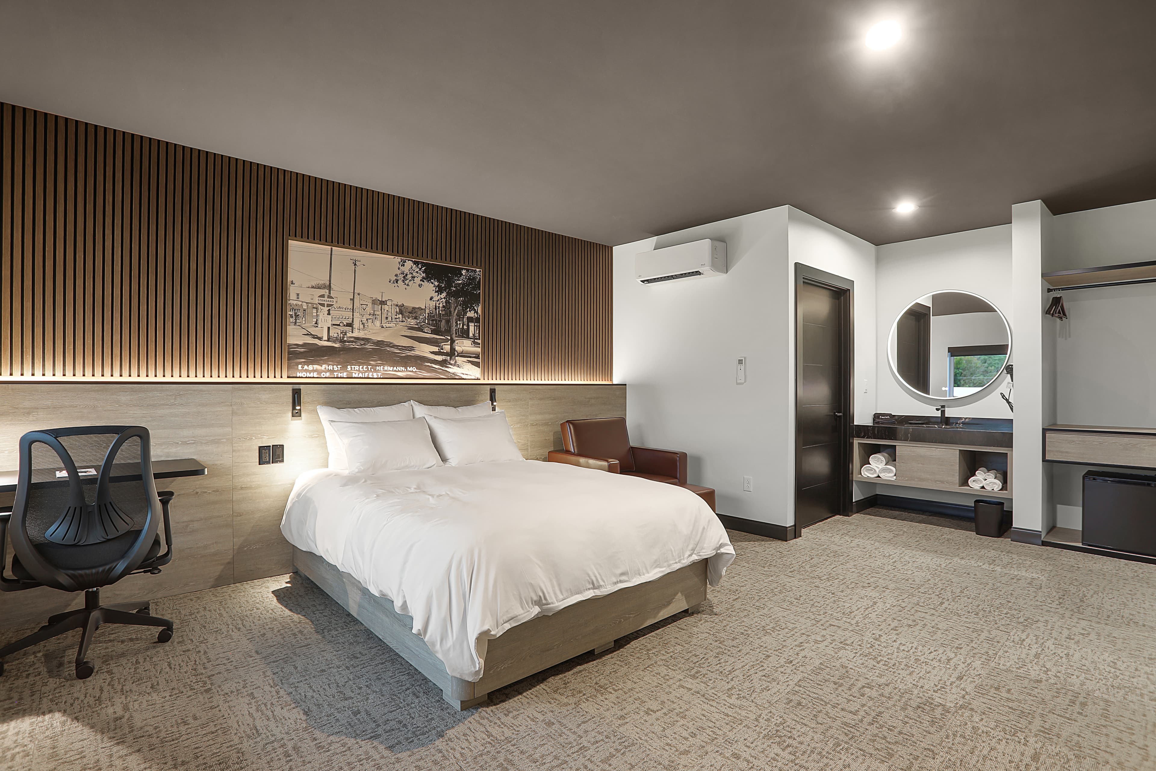 Modern hotel room featuring a queen bed, desk, and minimalist decor.