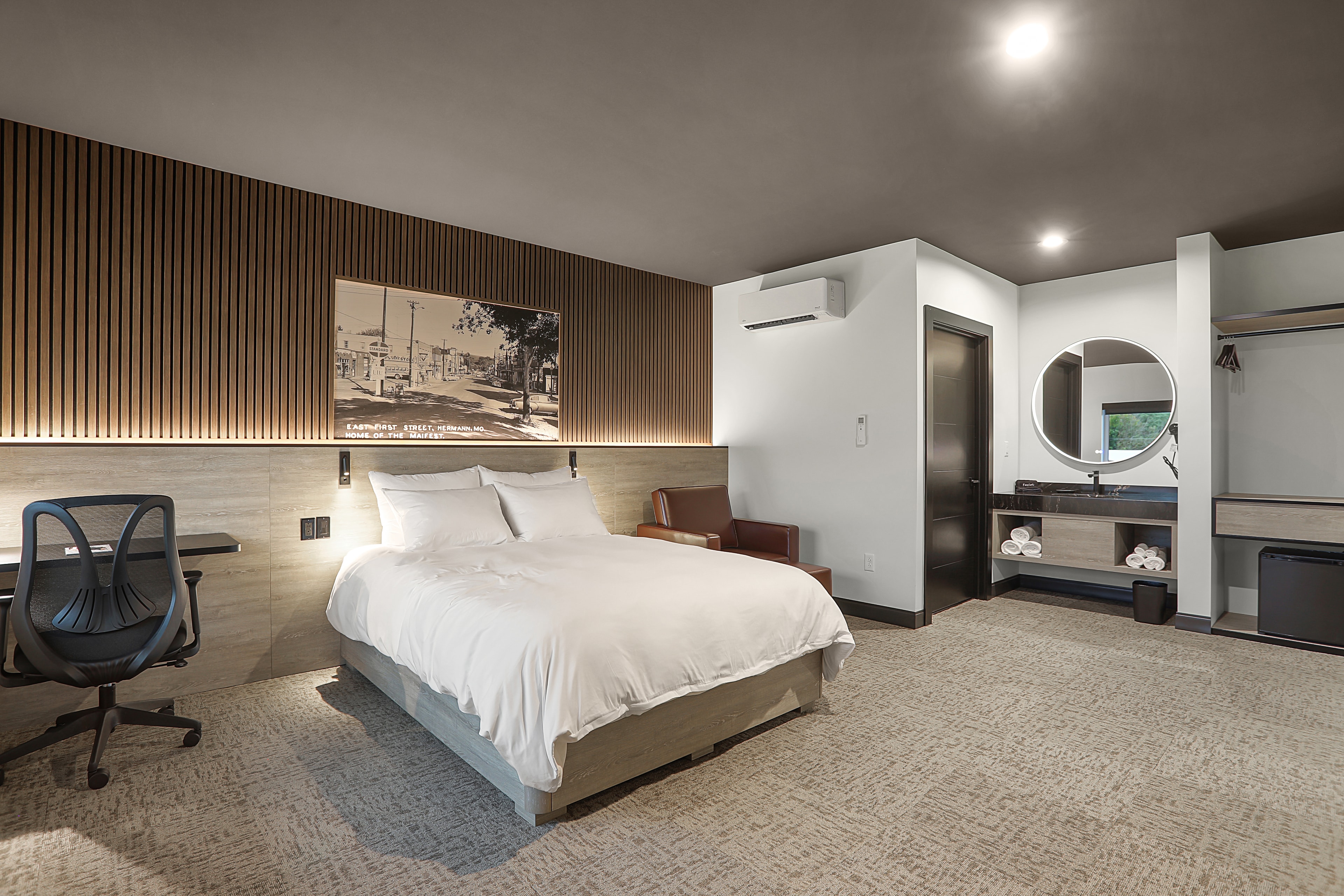 Modern hotel room featuring a queen bed, desk, and minimalist decor.